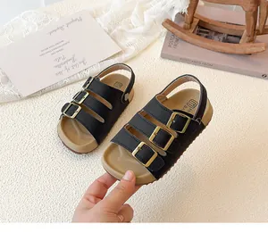 Close-up of black children's sandals with golden buckles and cork footbed