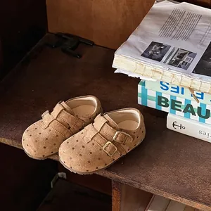 Macro detail showing brown polka dot suede texture and vintage metal buckles on girls' shoes