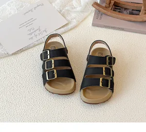 Top view of kids black three-strap sandals with cork soles and gold buckles