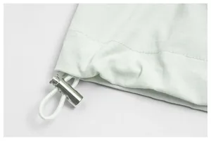 Close-up of adjustable drawstring with silver cord lock on mint green jacket hemline