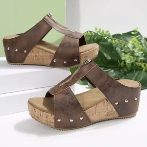Close-up detail of brown wedge sandals featuring a stylish front zipper and silver studs