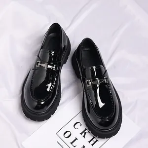 Nahaufnahme von schwarzen Herren-Loafers aus Lackleder mit dicker Sohle und Metallschnalle
