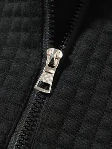 Detaillierte Makroansicht des Metallreißverschlusses und des schwarzen Waffelstrickgewebes.