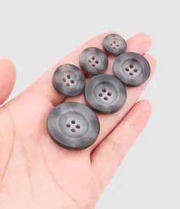 Close-up of premium grey marble-textured urea buttons in various sizes shown on a hand