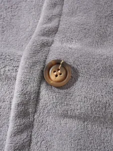 Close-up macro view showing soft grey coral fleece fabric texture and a brown marbled button