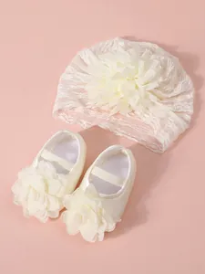 Detail of newborn baby lace turban hat and matching flower princess shoes in ivory
