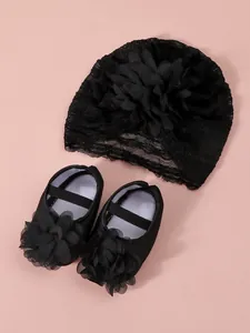 Detailed view of elegant black lace baby turban hat and matching floral infant princess shoes