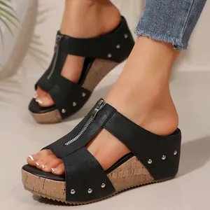 Detail view of women's black wedge sandals featuring front zipper and silver studs.