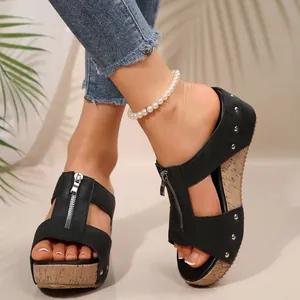 Detailed view of women's black wedge sandals featuring a front zipper and stylish metal studs