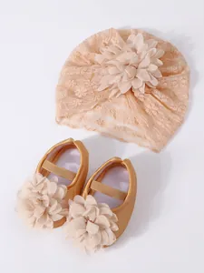 Close-up of newborn baby lace turban hat and matching gold floral princess shoes set