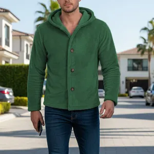 Male model wearing a green hooded coral fleece jacket in a sunny street setting