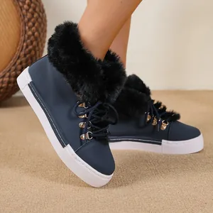 Detailed shot of navy blue snow boots with black faux fur trim and gold eyelets