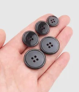 Close-up of high-quality dark marbled urea buttons showing various sizes held in a palm