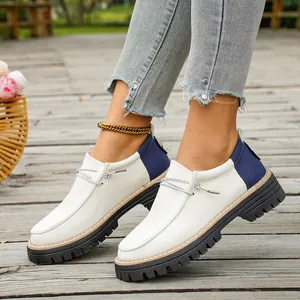Zijaanzicht van retro wit en blauw patchwork canvas loafers met dikke zool buiten