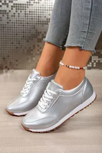 Κοντινό πλάνο με ασημί μεταλλικά γυναικεία sneakers με πλατφόρμα