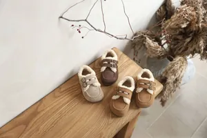 Mocassins en daim fourrés pour tout-petits aux tons neutres posés sur un banc