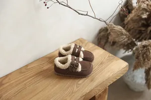 Chaussures polaires marron pour enfants sur un banc en bois avec décor naturel sec.