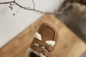 Gros plan sur la doublure en fausse fourrure et la boucle de ces chaussures en daim brun