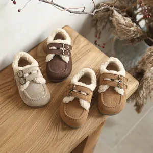 Mocassins d'hiver pour enfants doublés de fourrure dans des tons terreux sur un tabouret.