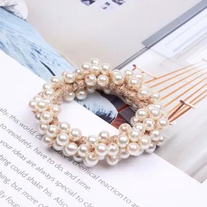 Detailed close-up view of elegant cream pearl beaded hair tie on stylish magazine background