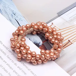 Close-up of an elegant rose gold pearl beaded hair tie on a magazine background.