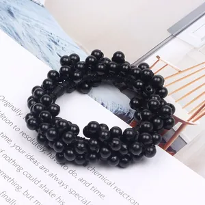 Close-up detail of a black beaded hair scrunchie on a lifestyle magazine background