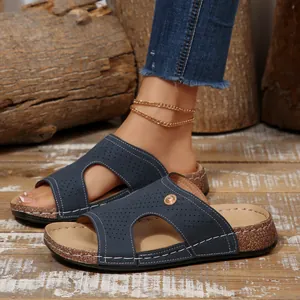 Dettaglio di sandali con zeppa blu navy traforati su sfondo di legno rustico