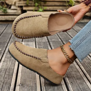 Close-up detail of stylish tan suede clogs with brown decorative stitching and thick sole.