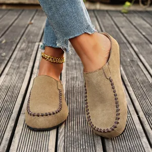 Close-up view of vintage suede clogs featuring hand-stitched detailing on a wooden deck.