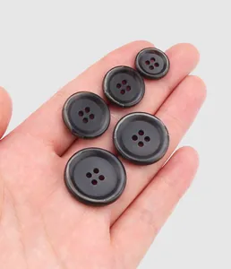 Detailed view of premium dark brown urea buttons in various sizes held in a palm
