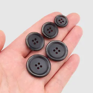 Premium dark urea resin buttons in five sizes shown in hand for high-end workwear