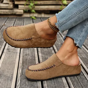Close-up detail of tan suede platform mules featuring decorative brown braided stitching.