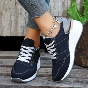 Κοντινό πλάνο με μπλε σκούρα γυναικεία sneakers με χοντρή λευκή σόλα και ασημί λεπτομέρεια.