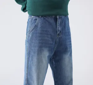 Détail d'un jean bleu large pour homme avec une petite étiquette blanche sur la poche latérale