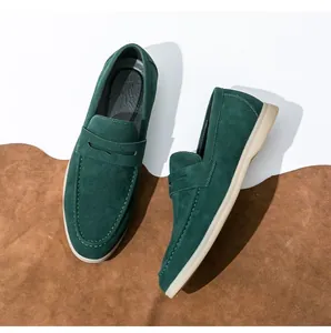 Top-down view of dark green suede penny loafers displayed on a rustic leather background