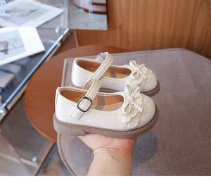 Detalle de merceditas color crema para niñas con encaje delicado y un lazo.