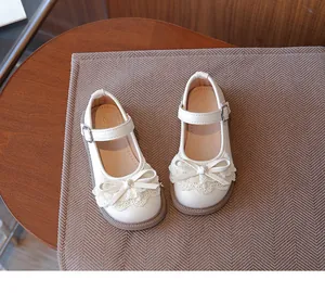 Vista detallada de zapatos Mary Jane blancos para niña con encaje y lazo elegantes