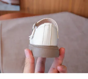 Primer plano de zapatos de cuero marfil para niñas con suela blanda marrón en el talón