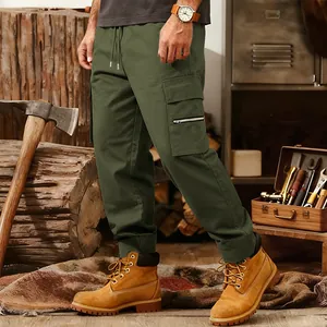 Detail of olive green men's tactical cargo pants with zipper pocket in a rugged setting