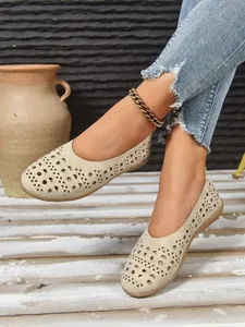 Detailansicht der beigen flachen Schuhe mit aufwendigen geometrischen Laserschnittmustern