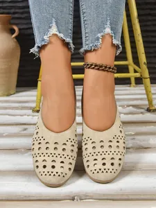 Detailansicht von stilvollen beigen perforierten flachen Schuhen mit blauer Denim-Jeans