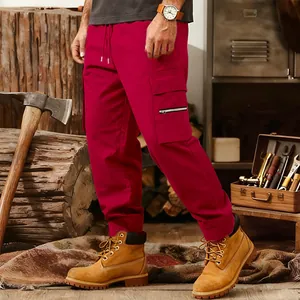 Close-up of red tactical cargo joggers for men in a rugged outdoor workshop setting