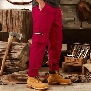 Detail view of red men's tactical cargo pants with multiple pockets in workshop setting.