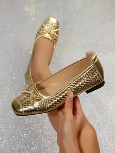 Close-up of golden woven ballet flats featuring a delicate bow detail and metallic finish