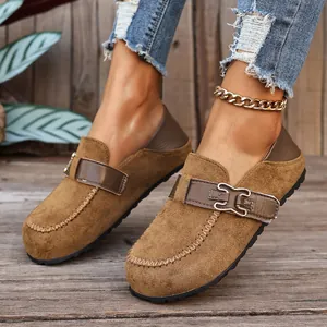 Détail de mocassins vintage en daim marron pour femme avec boucle métallique élégante.