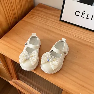 Close-up of cream mesh children's princess shoes with pearl bow and bunny detail