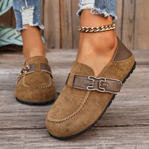 Détail de mocassins en daim marron avec boucle métallique et surpiqûres.