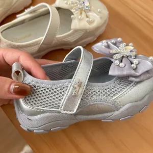 Detail of silver girl's princess shoe featuring breathable mesh and a pearl-studded bow
