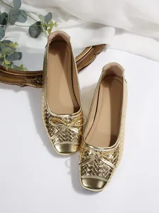 Detail view of golden ballet flats featuring woven texture and delicate bow accent.