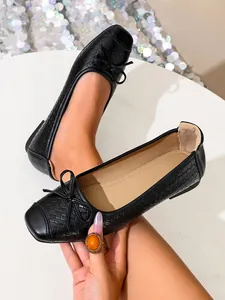 Close-up detail of stylish black woven ballet flats with square toe and cute bow accent.